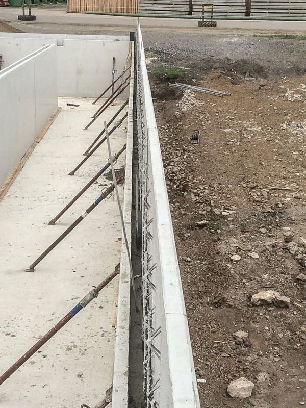 Neben einem Feld aus Erde wird eine Betonmauer errichtet.