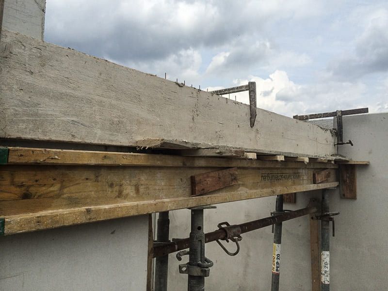 Ein Holzbalken liegt auf einer Betonwand.