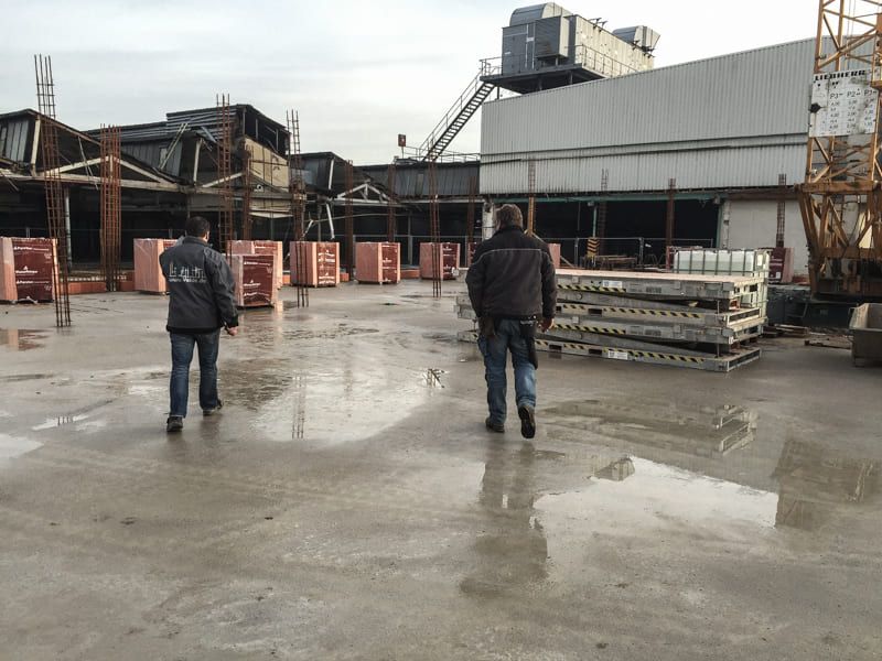 Zwei Männer gehen vor einem Gebäude, auf dem 