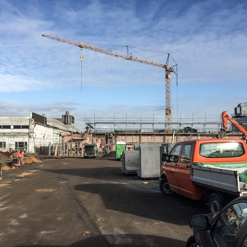 Eine Baustelle mit Lastwagen und einem Kran im Hintergrund