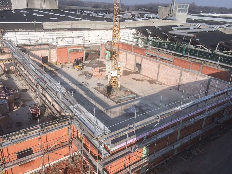 Eine Luftaufnahme einer Baustelle mit Gerüst und Kran.