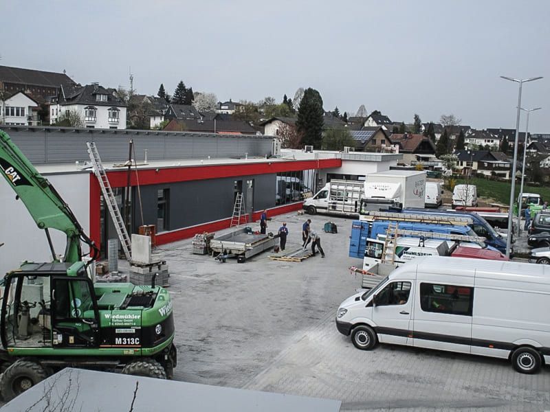 Viele Fahrzeuge sind vor einem im Bau befindlichen Gebäude geparkt