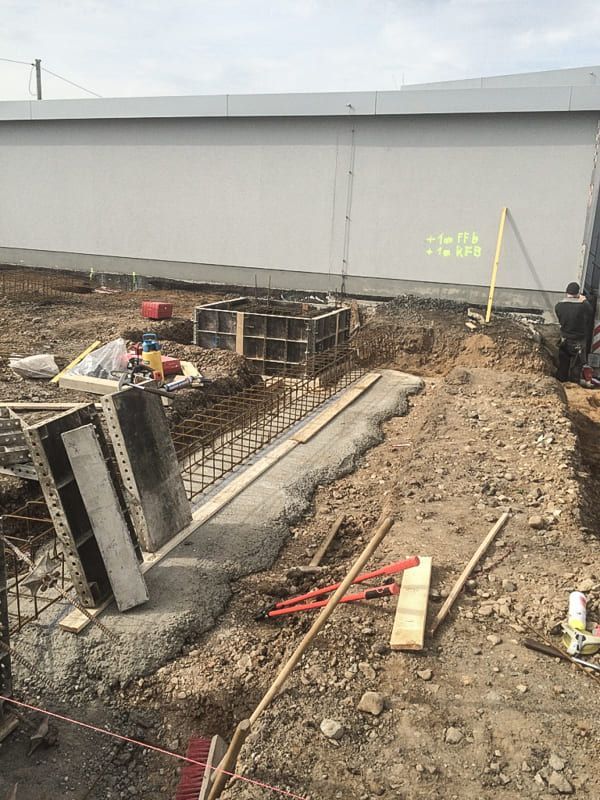 Eine Baustelle mit einem Gebäude im Hintergrund und vielen Werkzeugen im Dreck.