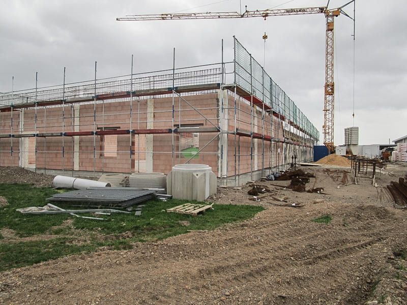 Ein im Bau befindliches Gebäude mit Gerüsten und einem Kran im Hintergrund