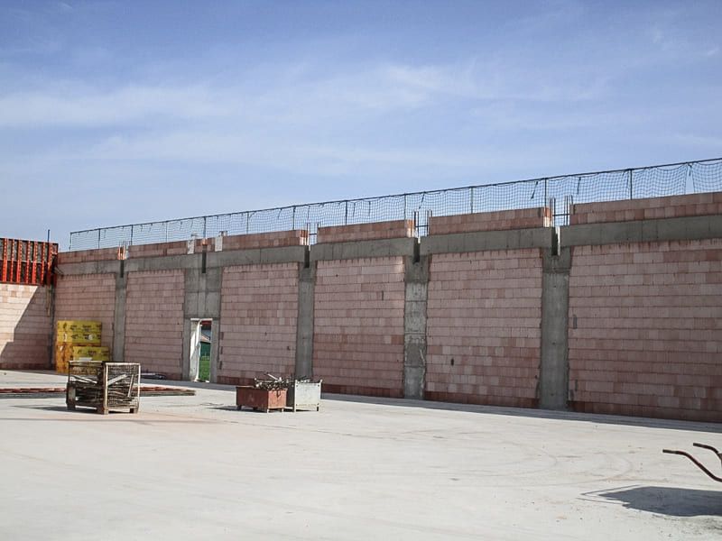 Auf einer Baustelle wird eine große Ziegelmauer gebaut.