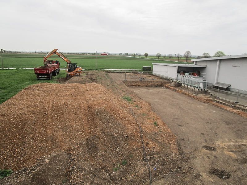 Vor einem Gebäude liegt ein großer Erdhaufen.