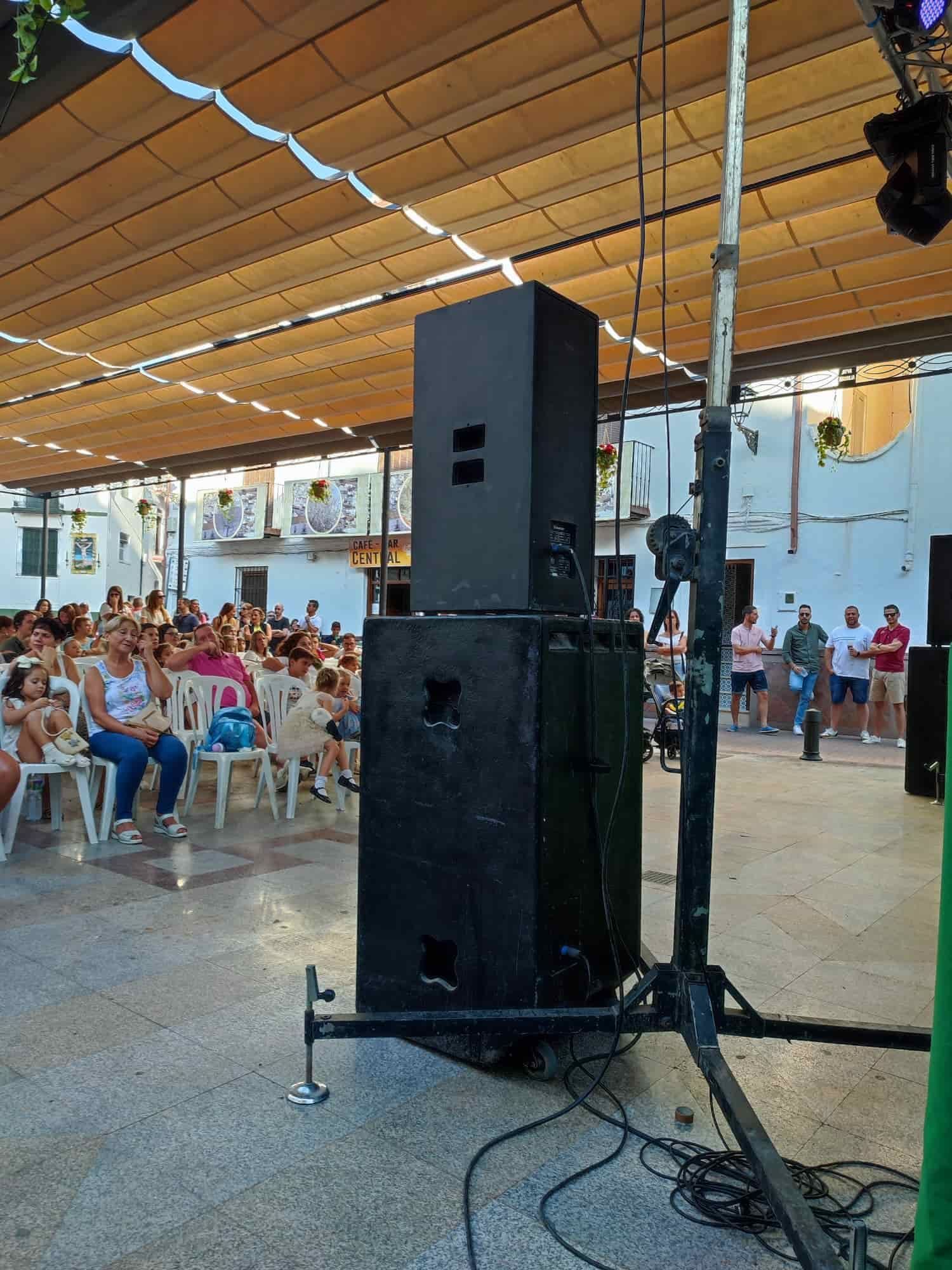 Oradores negros en el escenario, multitud sentada en un lugar al aire libre con decoraciones blancas.