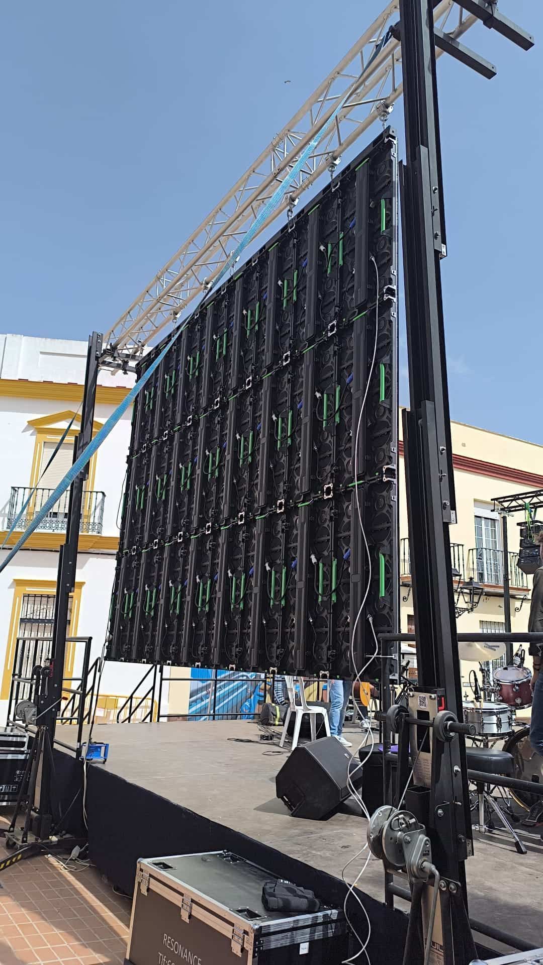 Montaje de escenario con gran pantalla de vídeo, estructura metálica y equipo de sonido al aire libre.