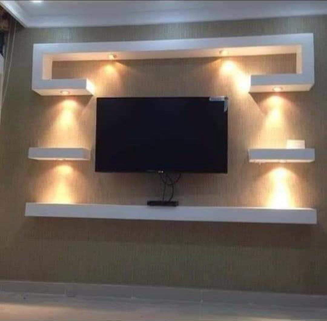 Un televisor de pantalla plana está montado en una pared encima de un estante.