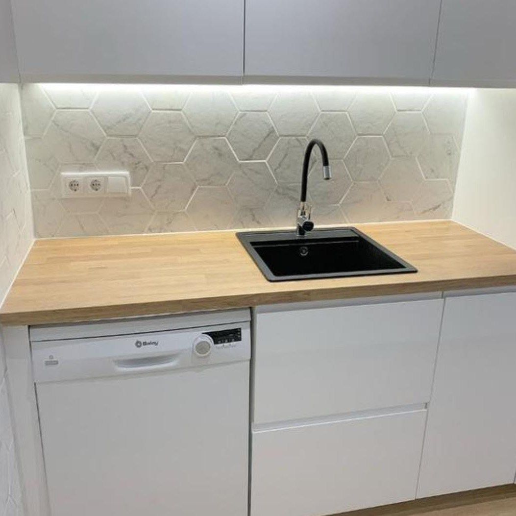 Una cocina con fregadero, lavavajillas y encimera de madera.