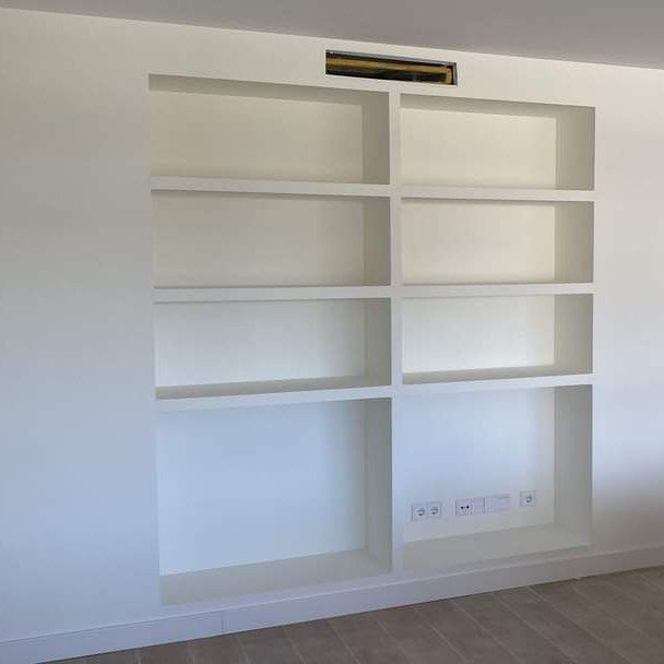 Una habitación con una pared blanca y estantes y un ventilador de techo.