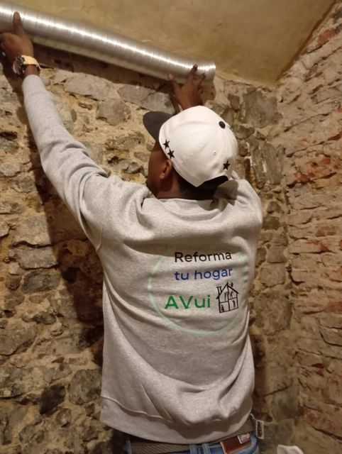Un hombre que lleva una sudadera gris y un sombrero blanco está trabajando en una tubería.
