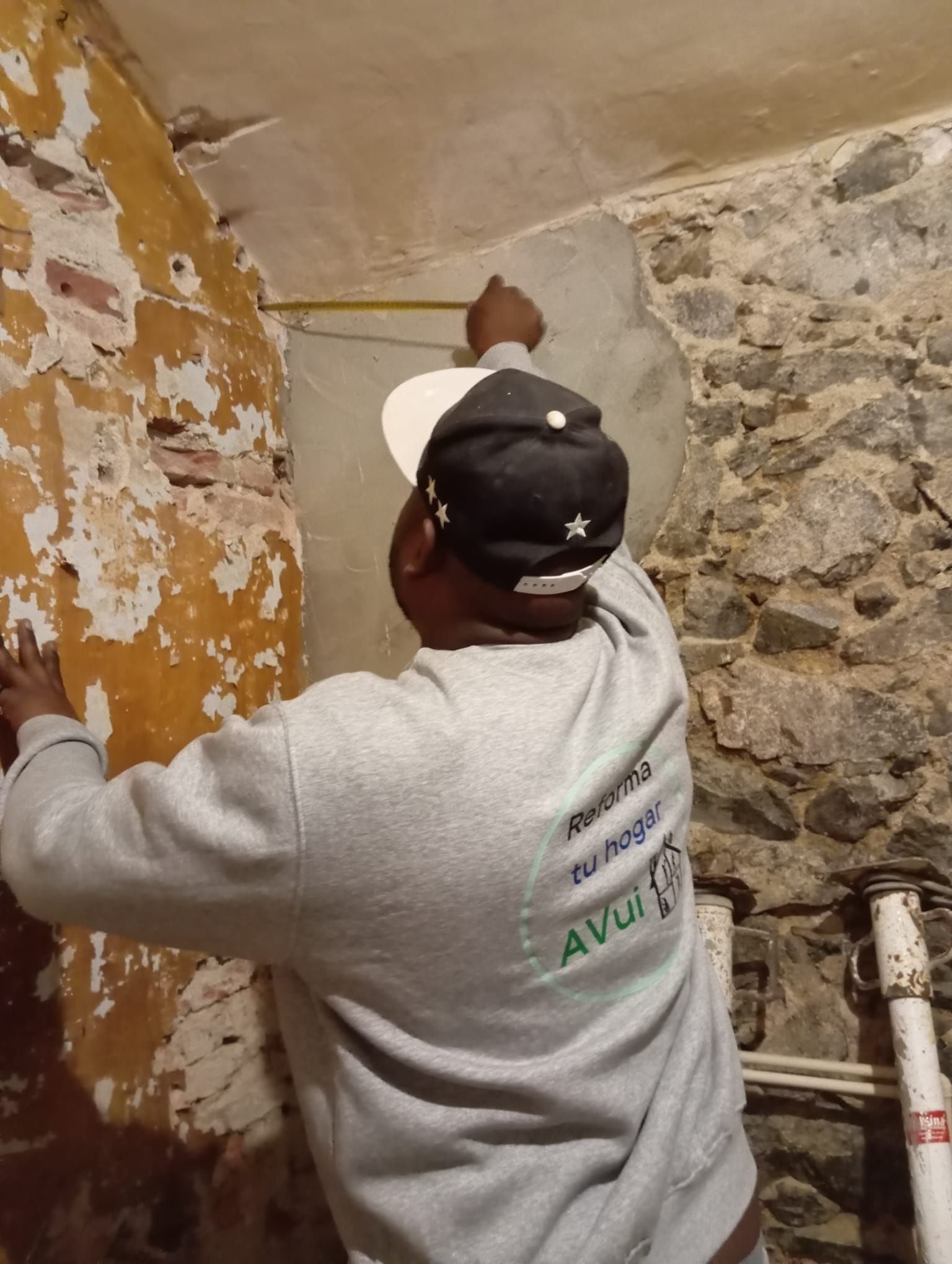 Un hombre está midiendo una pared con una cinta métrica.