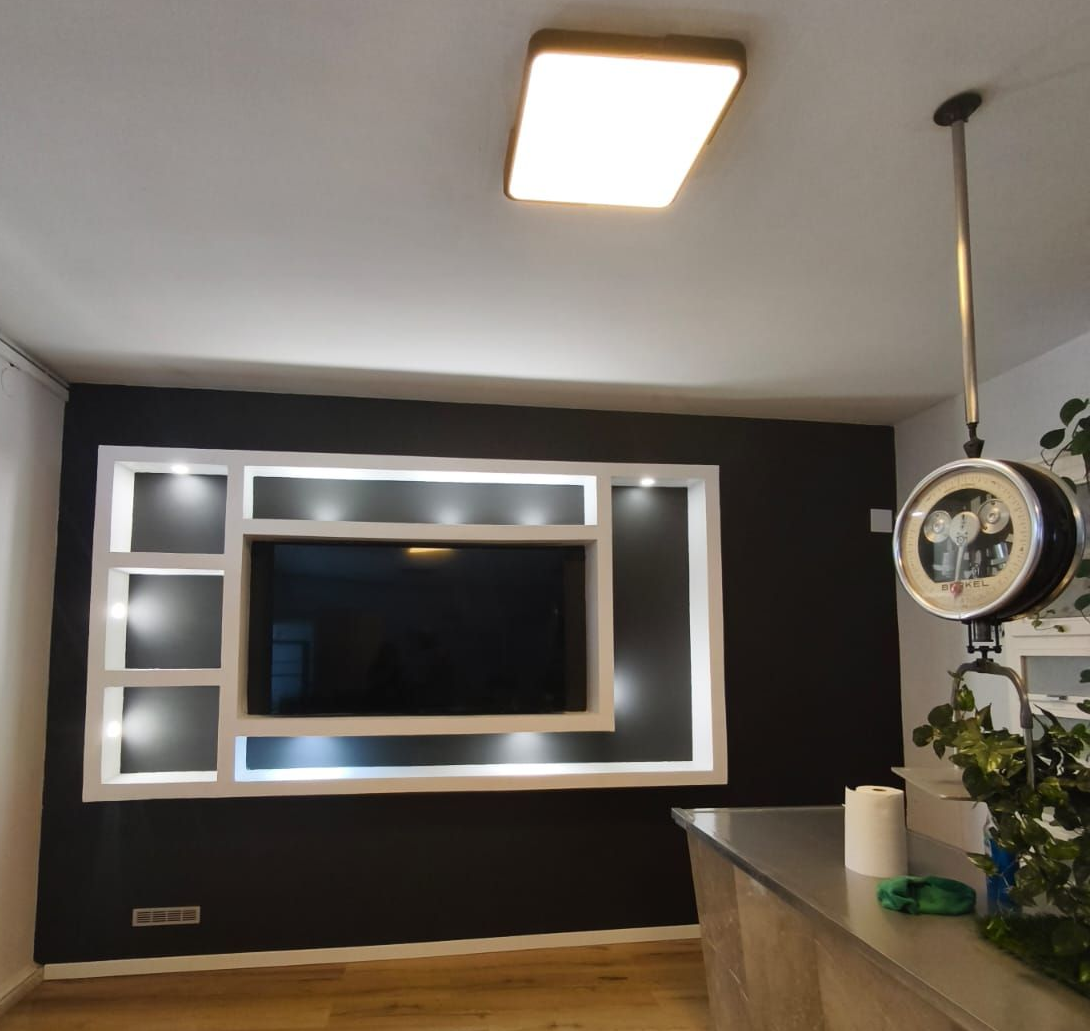 Una sala de estar con una pared blanca y un televisor montado en ella.