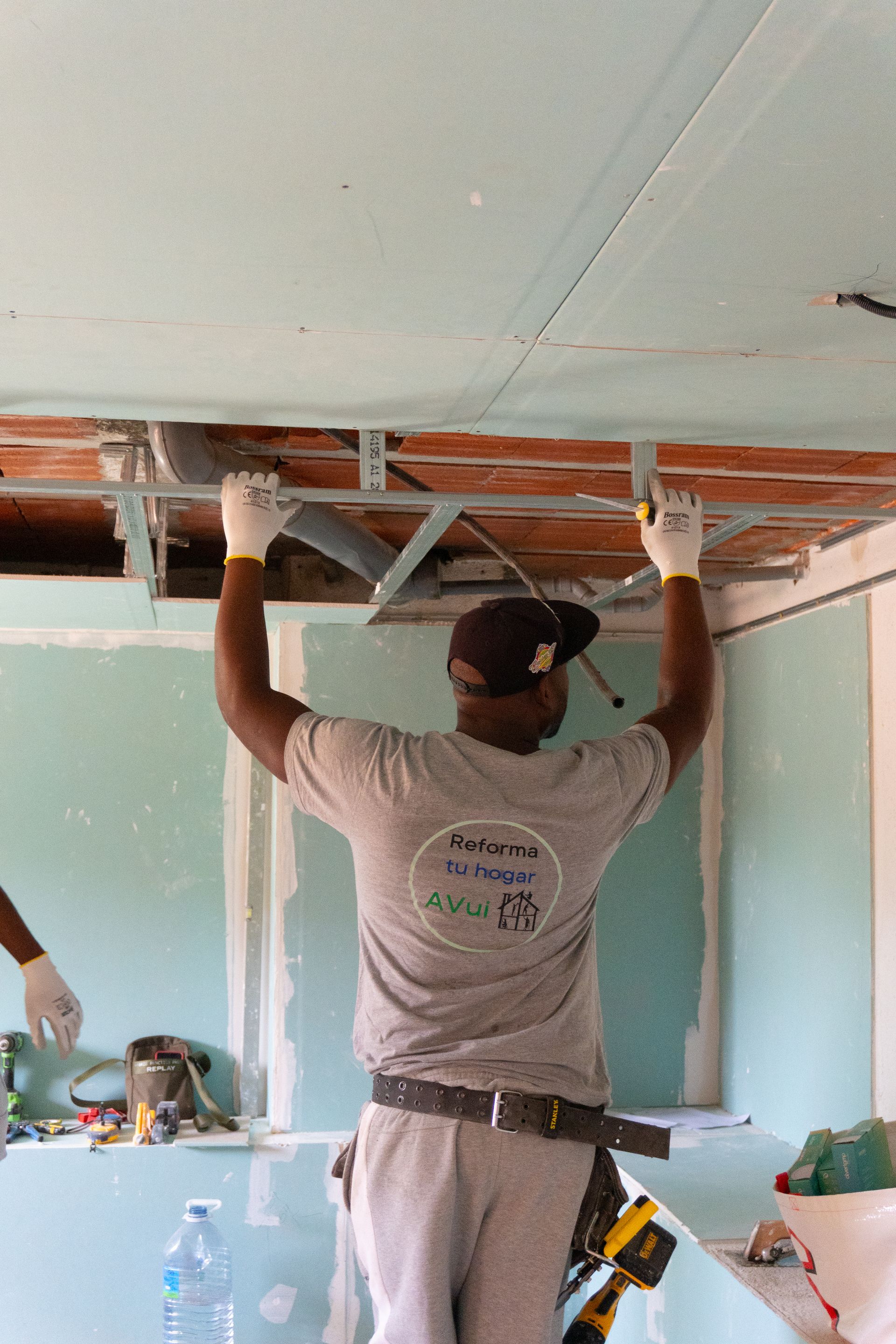 Un hombre en una escalera midiendo una pared con una cinta métrica