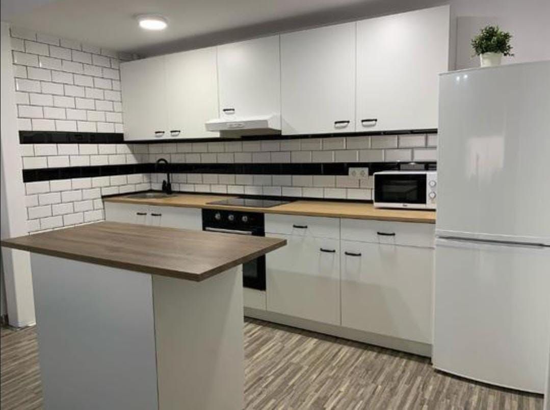 Una cocina con gabinetes blancos y una encimera negra.