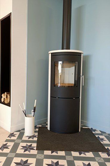 Un poêle moderne noir et blanc avec un tuyau de cheminée dans le coin d'une pièce avec du carrelage à motifs