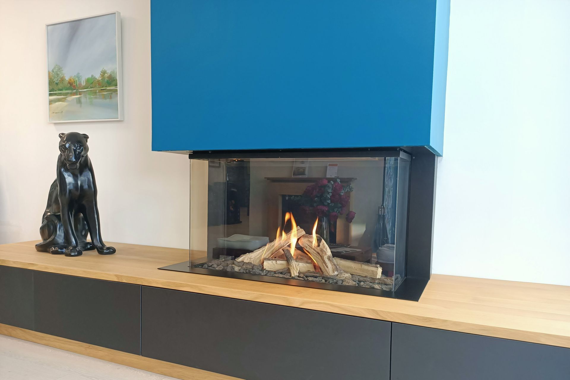 Cheminée moderne avec accent bleu, manteau en bois, armoires noires et sculpture