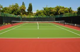 Una cancha de tenis con una red y árboles al fondo.