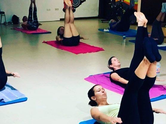 Un grupo de personas está haciendo yoga en colchonetas en un gimnasio.