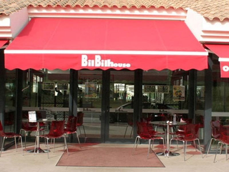 Un restaurante con mesas y sillas bajo un toldo que dice bibihouse