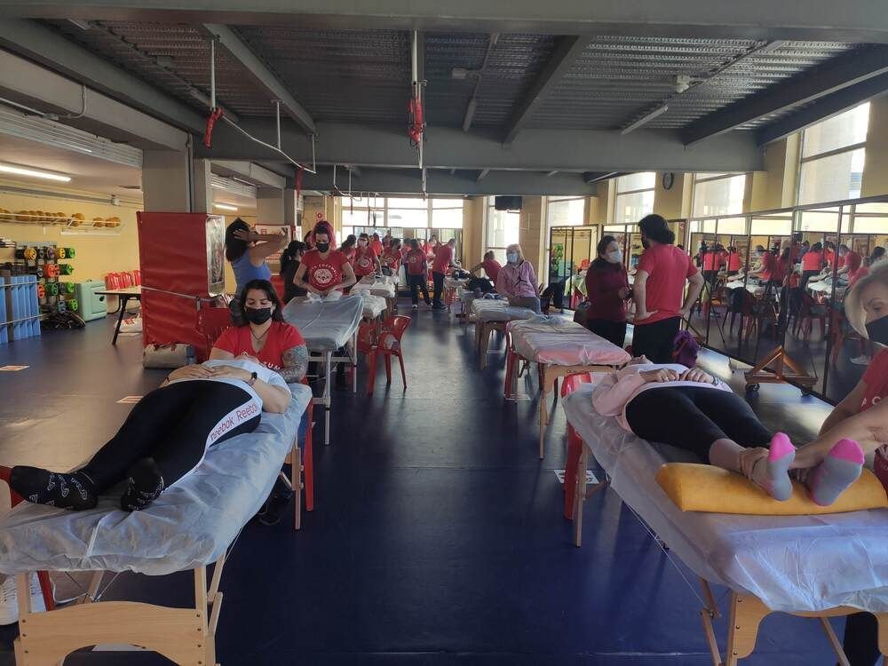 Un grupo de personas están acostadas sobre mesas en un gimnasio.