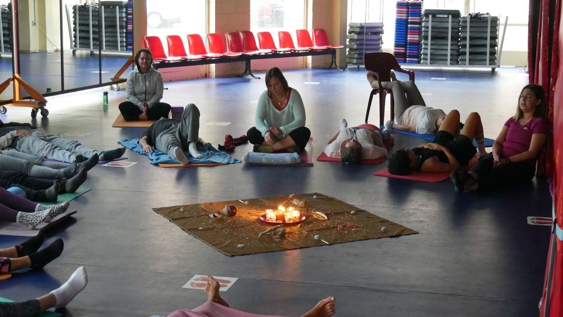 Un grupo de personas está sentado alrededor de un fuego en un gimnasio.