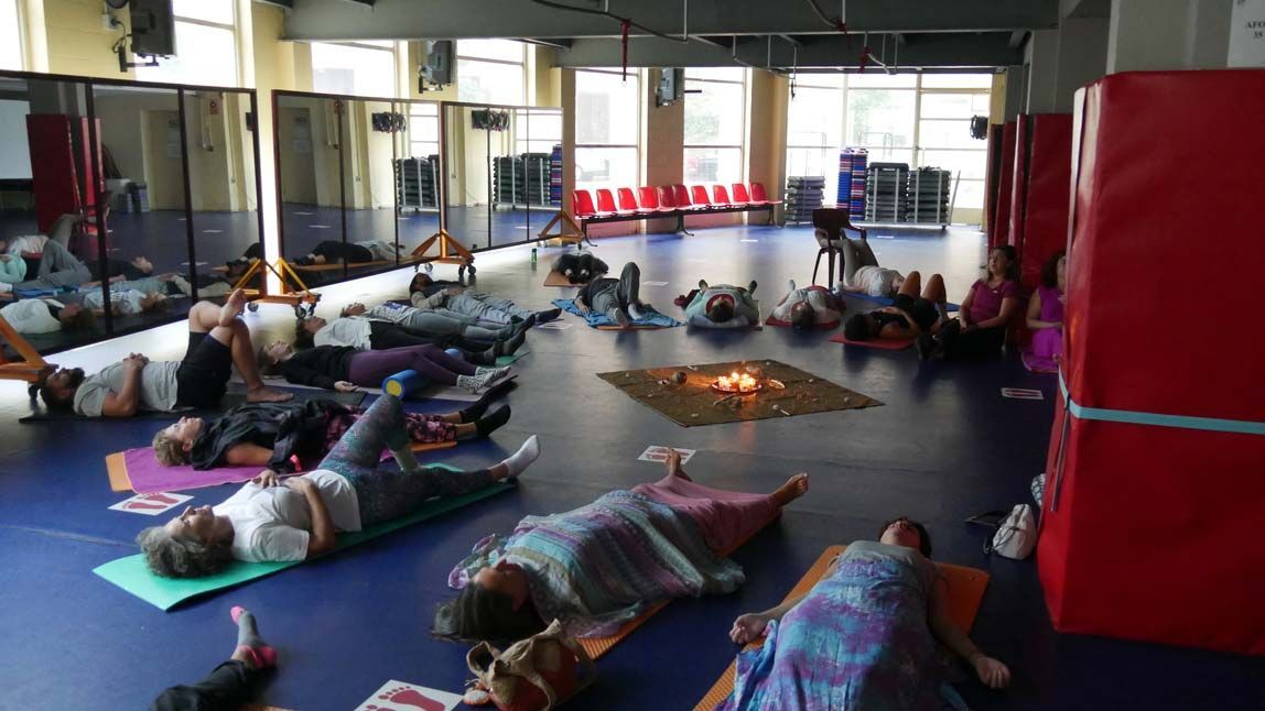 Un grupo de personas tumbadas sobre colchonetas de yoga en un gimnasio.