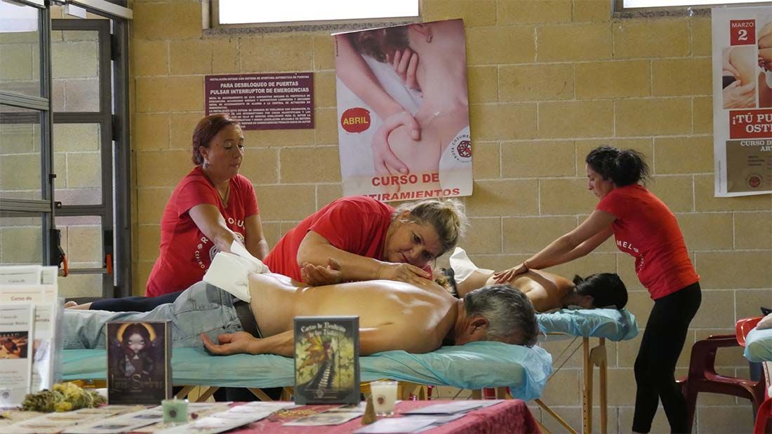 Dos mujeres con camisas rojas le están dando un masaje a un hombre.