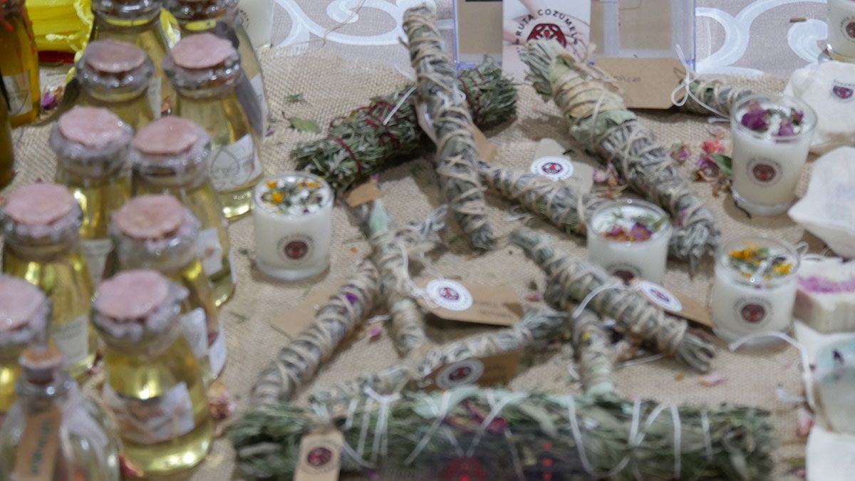 Una mesa cubierta con velas, palitos de salvia y botellas de aceite.