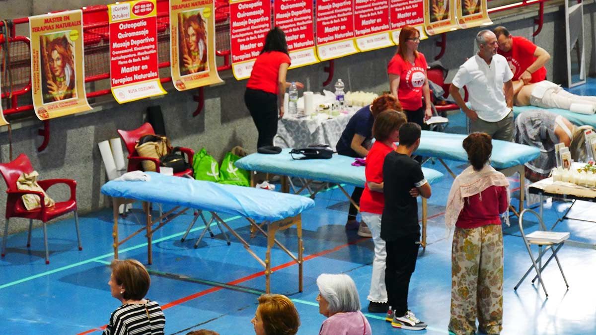 Un grupo de personas de pie alrededor de mesas plegables en un gimnasio.