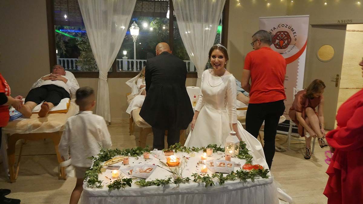 Una novia y un novio están de pie frente a un pastel de bodas.