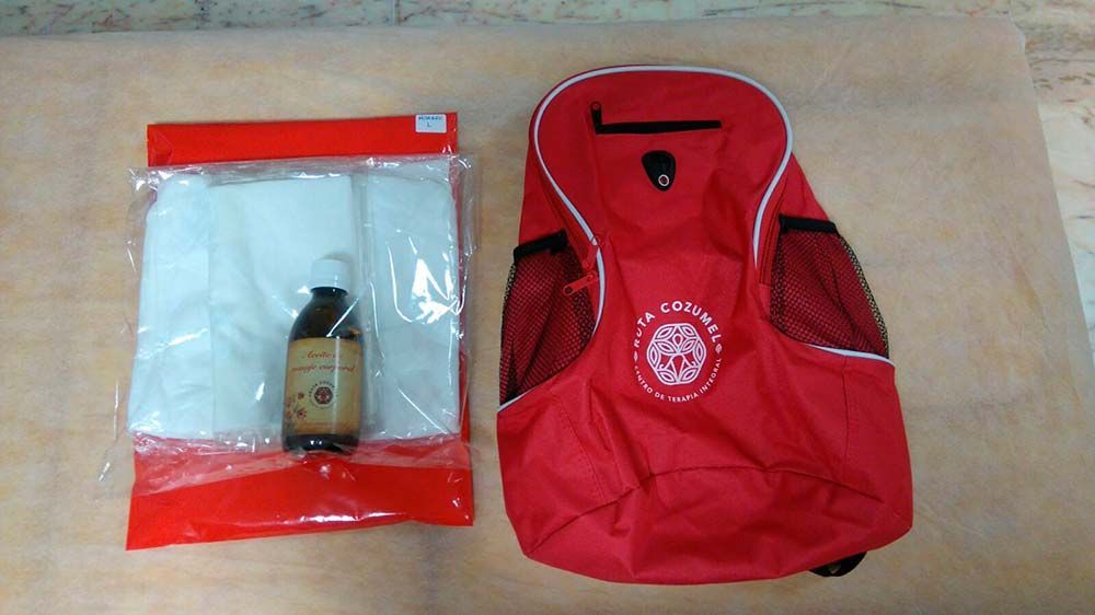 Una mochila roja se encuentra junto a una bolsa blanca.