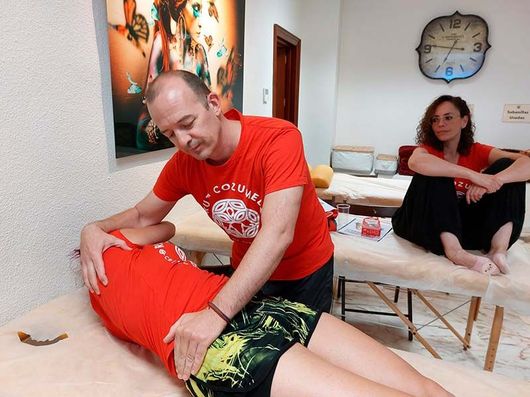 Un hombre con una camisa roja le está dando un masaje a una mujer.