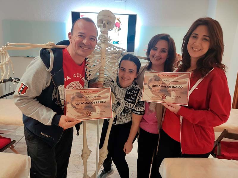 Un grupo de personas sosteniendo certificados frente a un esqueleto.