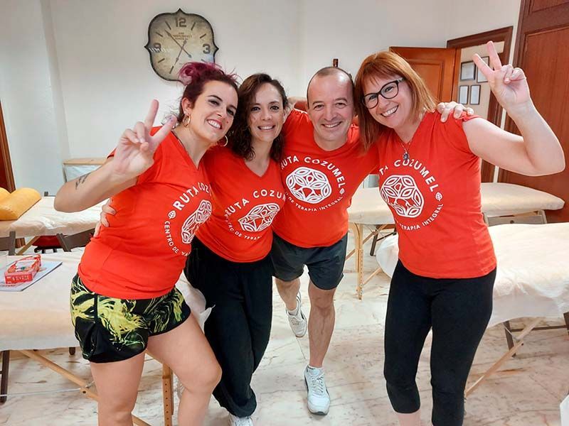 Un grupo de personas posa para una foto y una de ellas lleva una camiseta naranja.