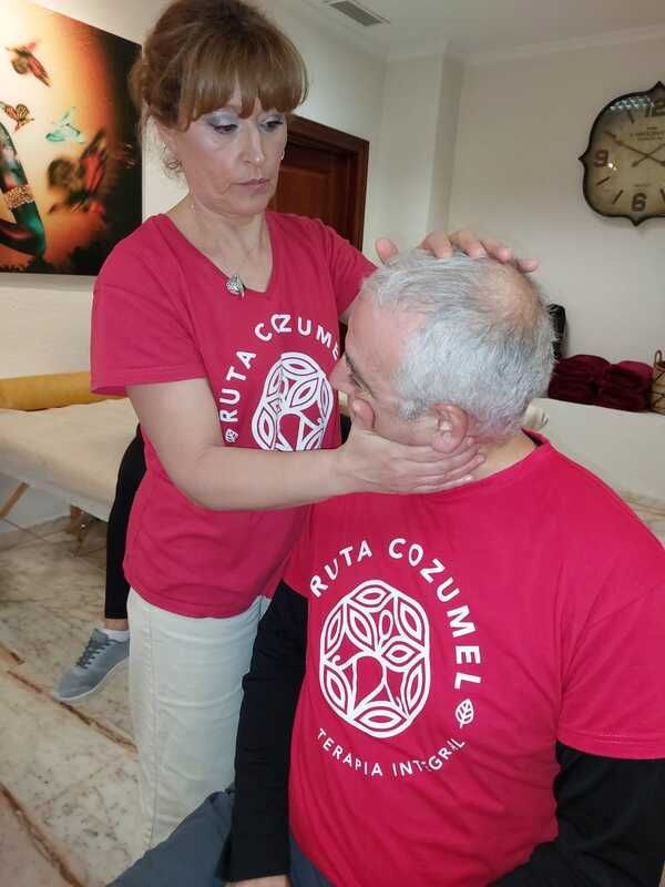 Una mujer le está dando un masaje a un hombre mientras viste una camisa roja que dice Ruta Cozumel.