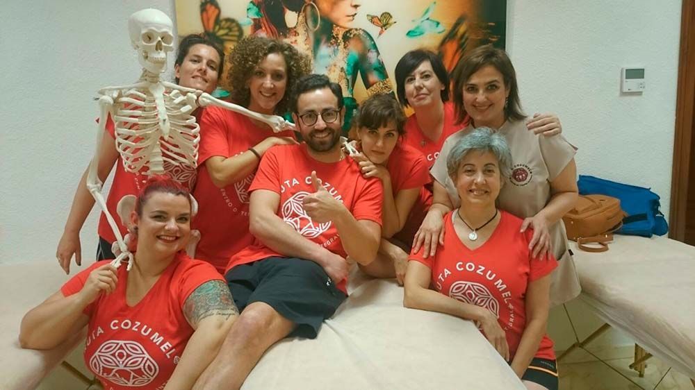 Un grupo de personas posando para una foto con un esqueleto en el medio.