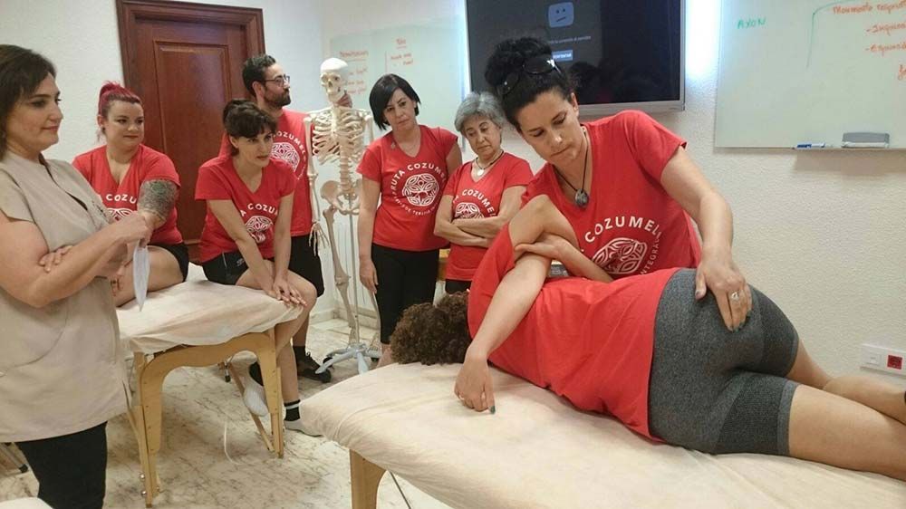 Una mujer con una camisa roja le está dando un masaje a otra mujer.