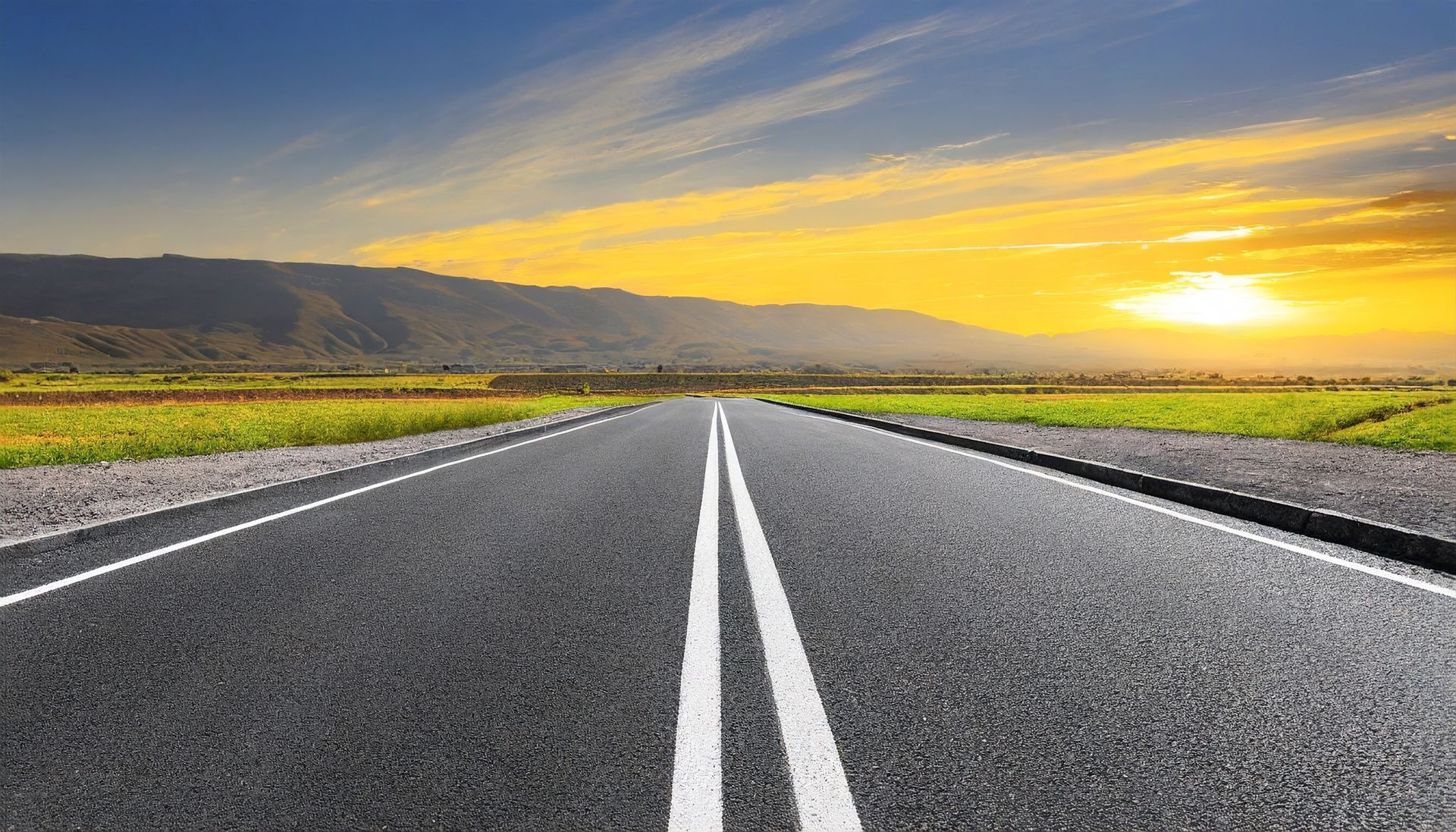 Un'autostrada deserta con un tramonto sullo sfondo.