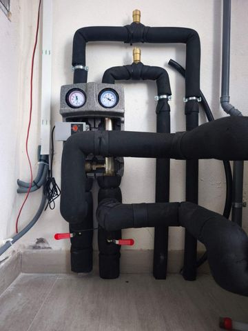 Tuberías aisladas con manómetros y válvulas en una pared de una sala de instalaciones