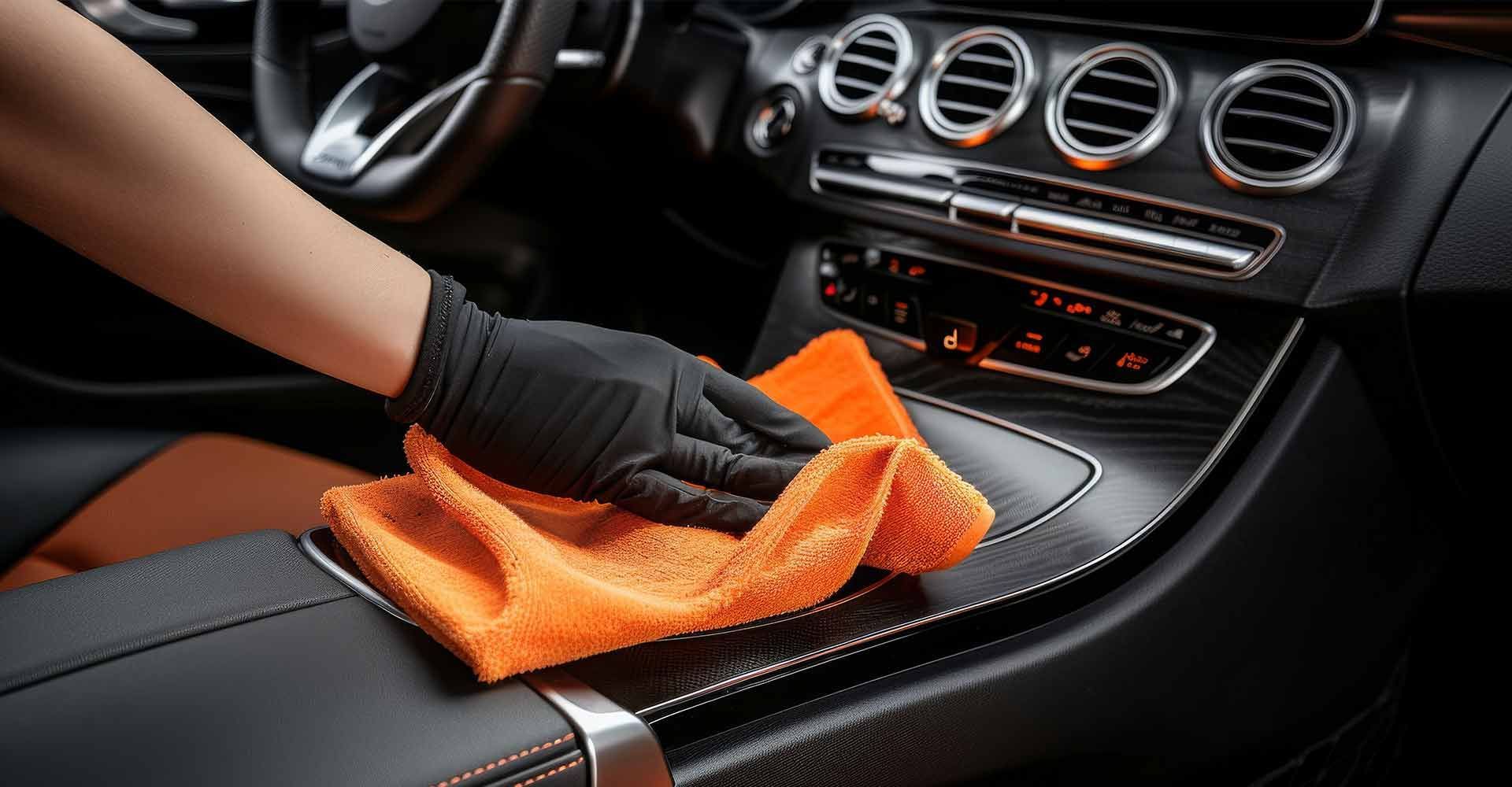 Eine Person reinigt den Innenraum eines Autos mit einem Handtuch.