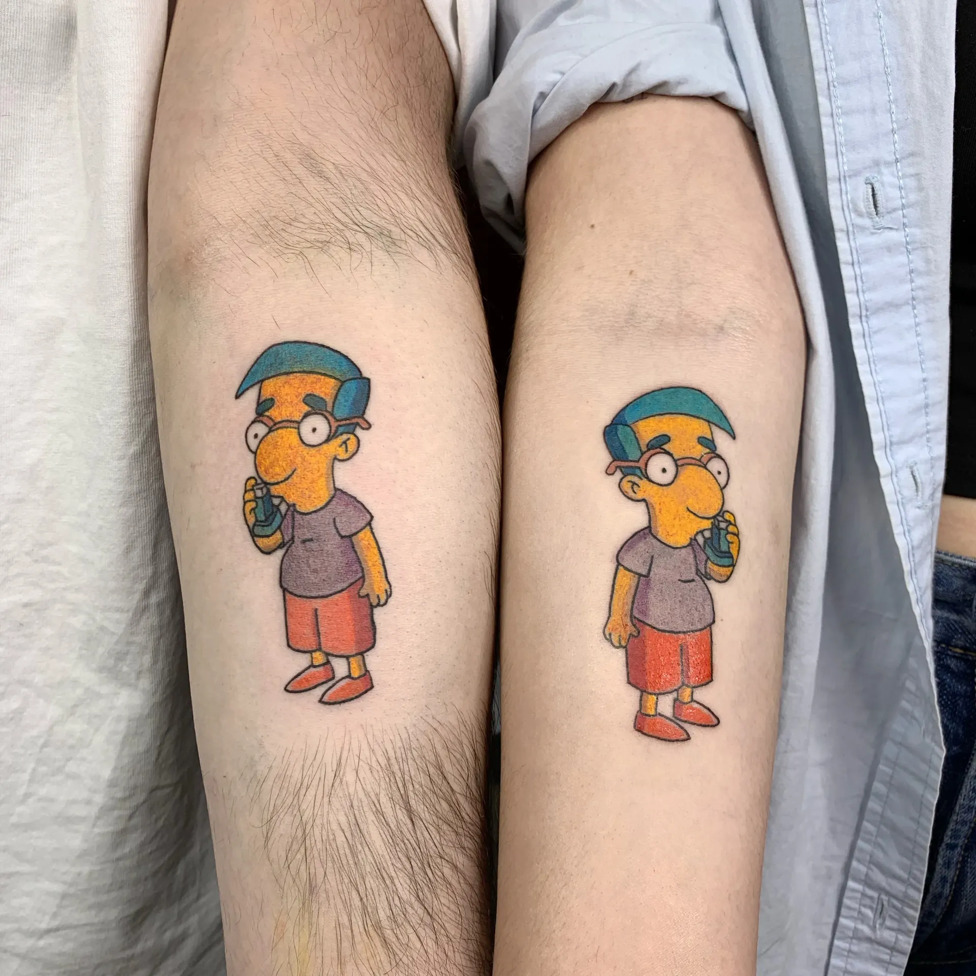 Tatuador con guantes negros, utilizando una máquina para aplicar un diseño floral en un brazo con un tatuaje parcial rojo y negro.