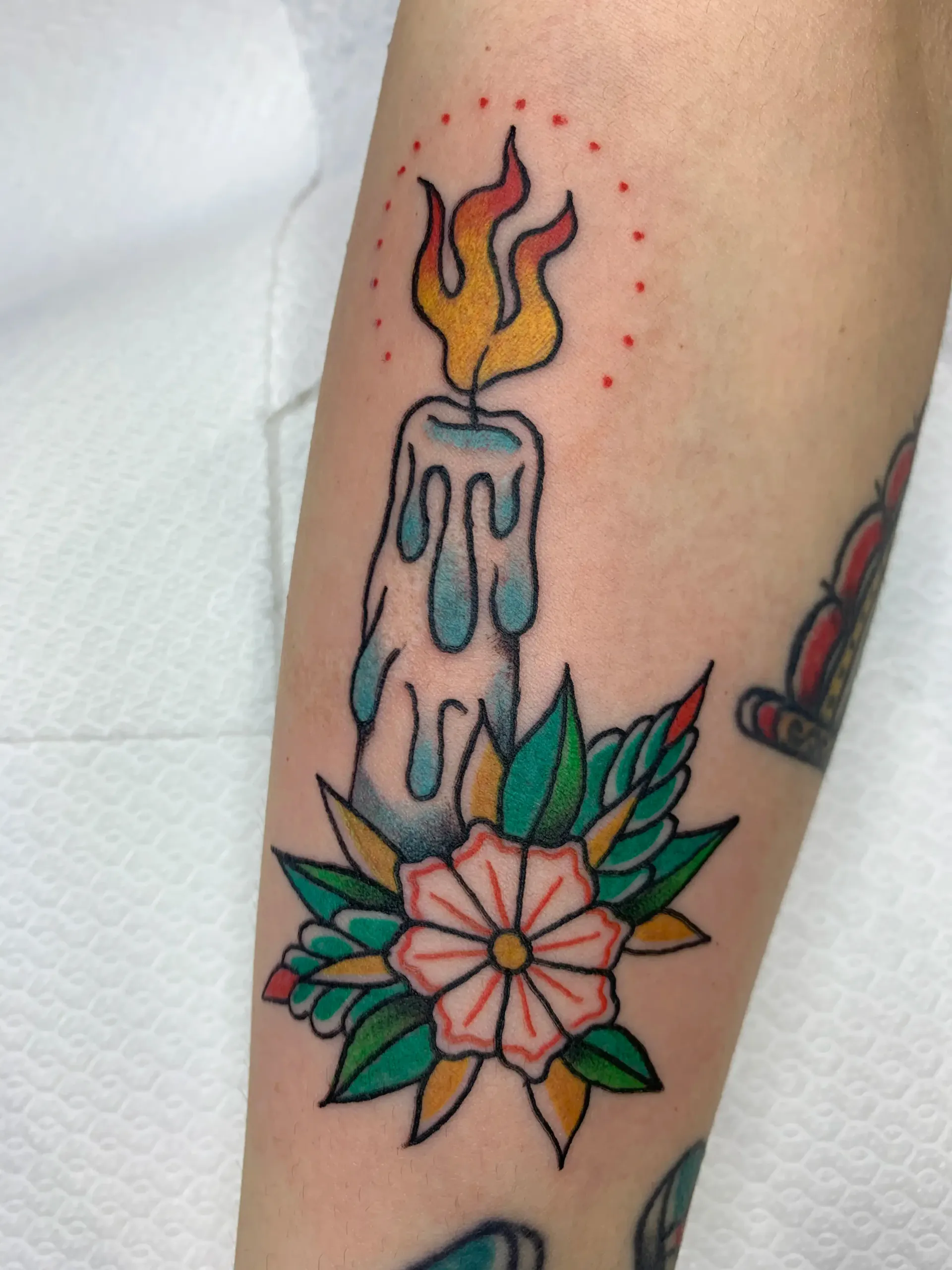 Tatuador con guantes negros añadiendo color a un tatuaje de un zorro en el muslo de una persona.