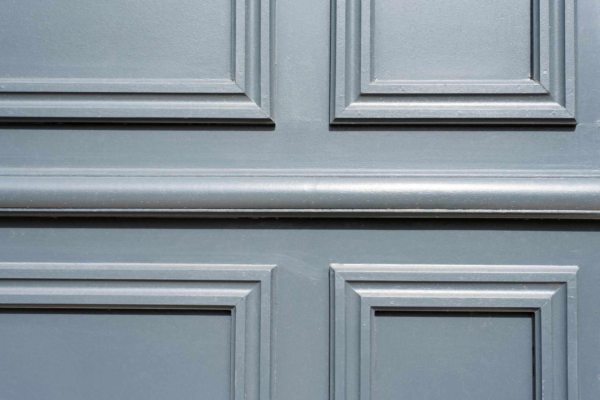 Gros plan sur une armoire ou une porte à panneaux bleu clair avec moulure rectangulaire en relief.