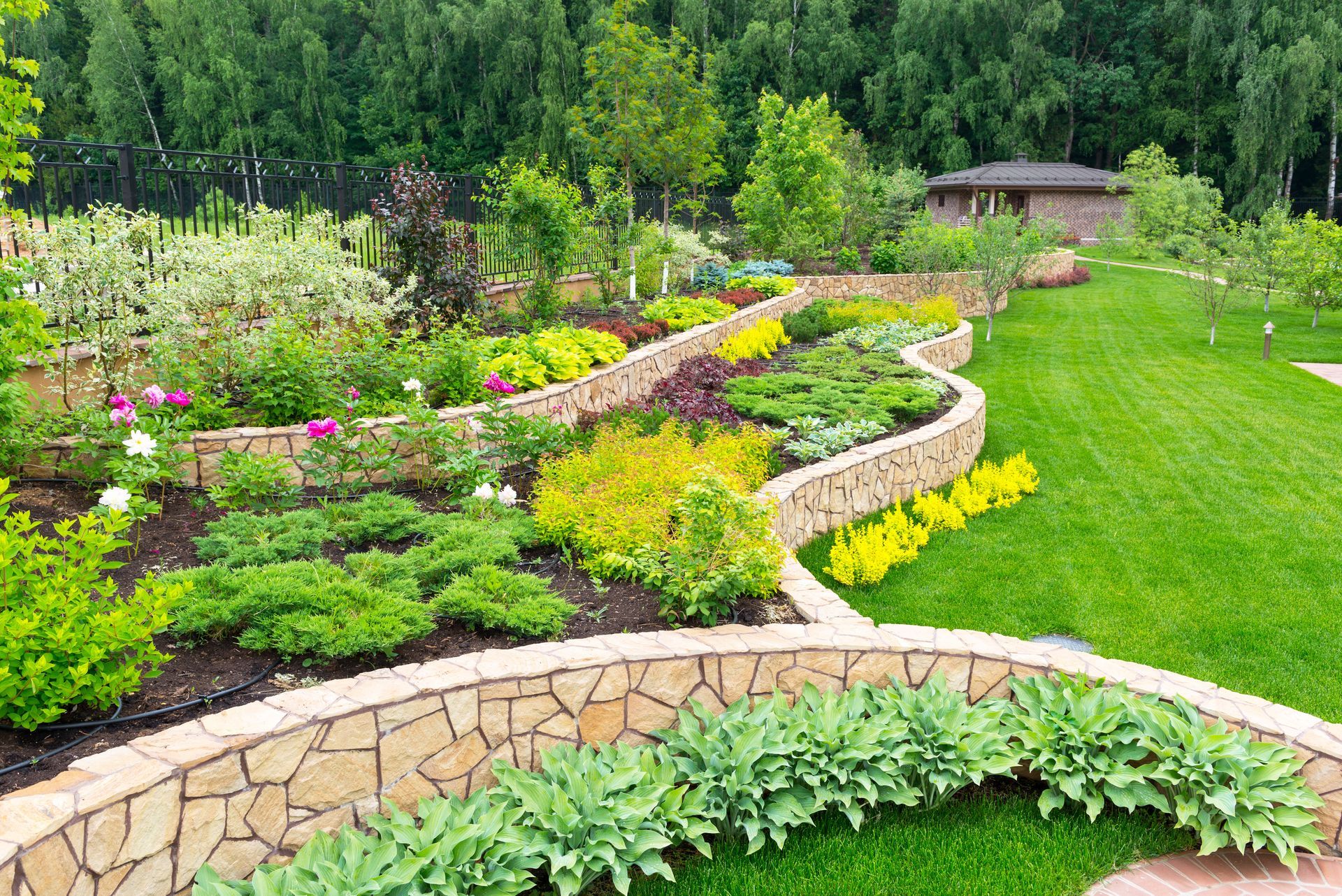 Jardinières en pierre incurvées avec fleurs colorées et verdure sur une colline aménagée