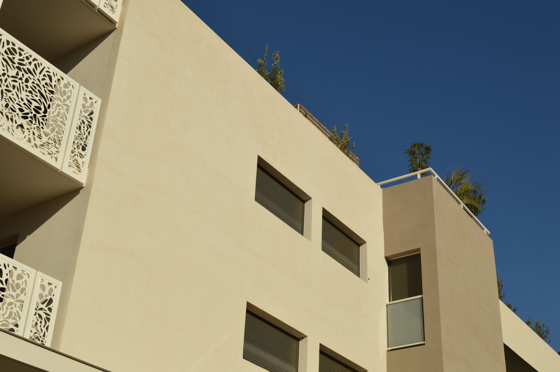 Immeuble d'appartements moderne beige avec balcons se détachant sur un ciel bleu clair
