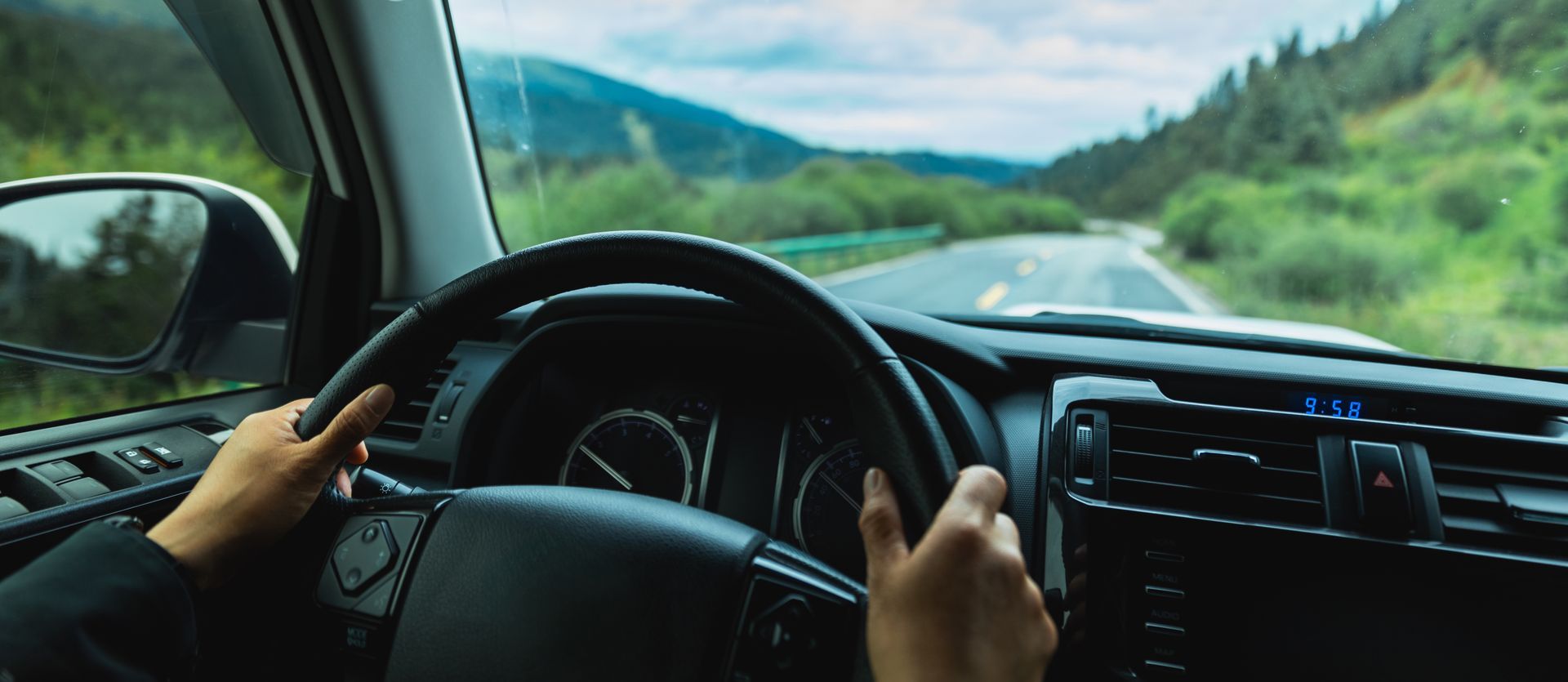Main sur un volant qui conduit sur une route en Martinique