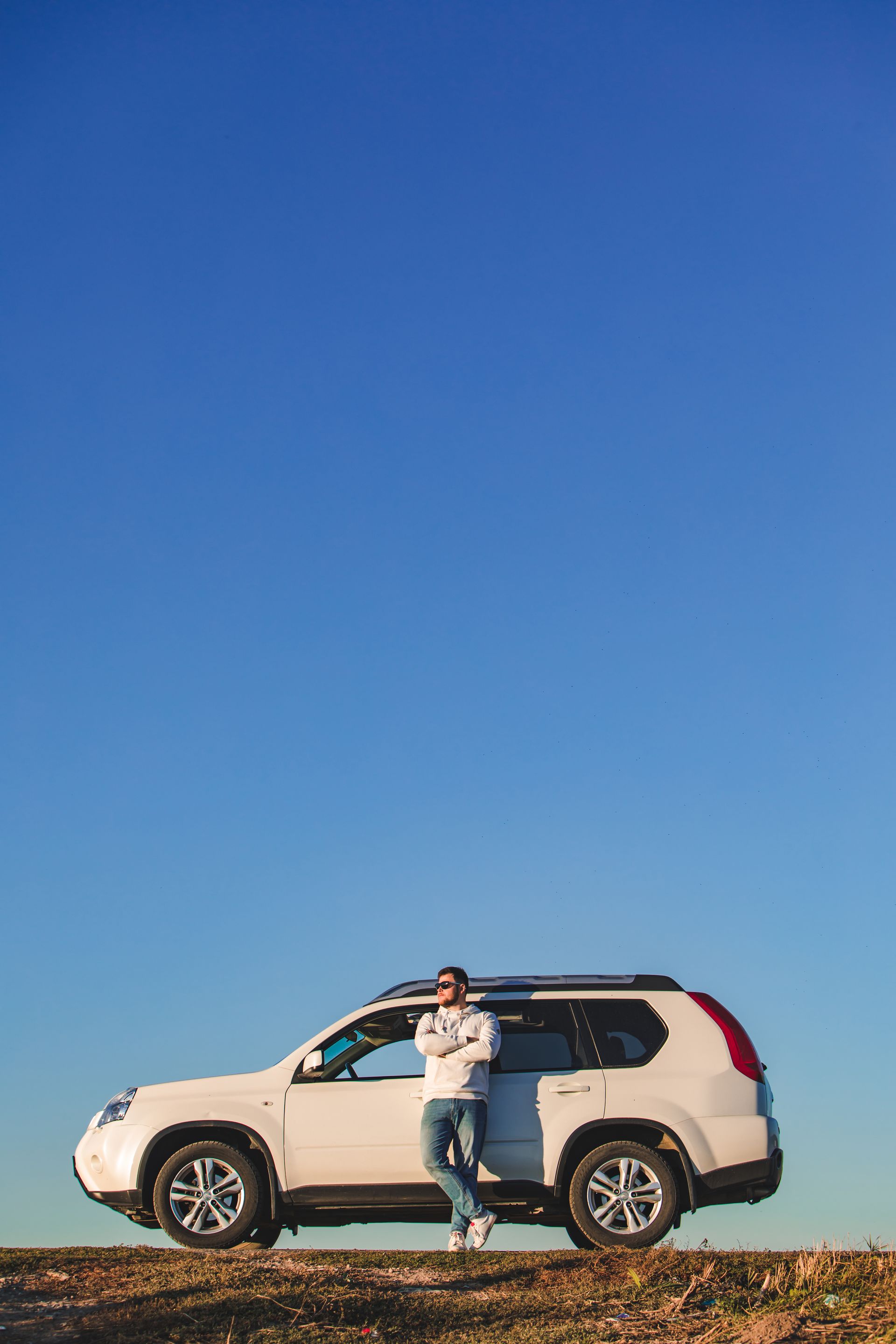 Homme sur le bord de la route adossé à sa voiture