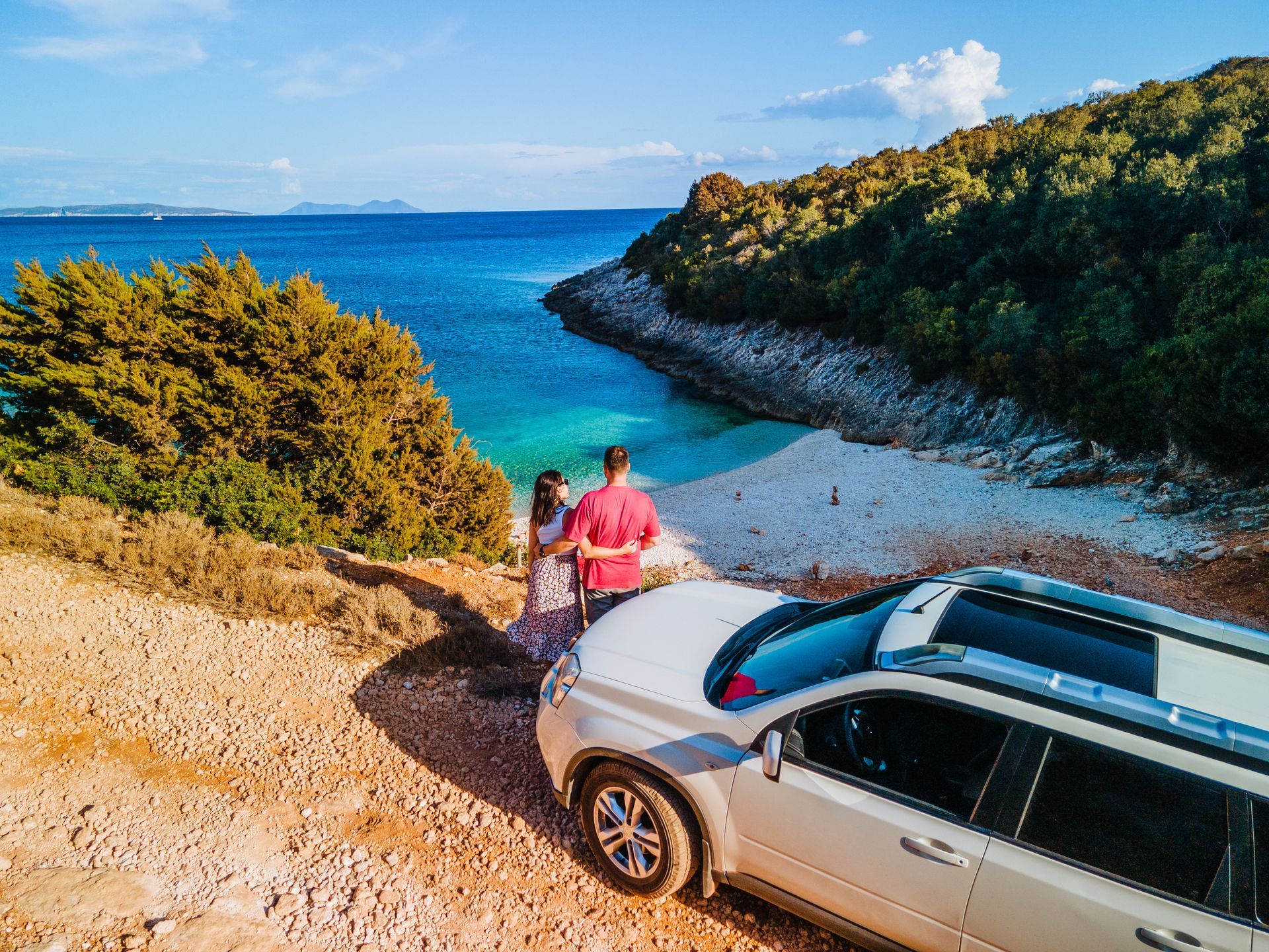 Couple devant leur voiture qui regarde la plage